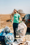 Man picking up rubbish by field, Georgetown, Canada