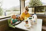 Mother feeding baby breakfast in motorhome