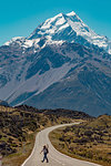 Hiker crossing road leading towards mountains, Wanaka, Taranaki, New Zealand