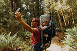 Father with baby taking selfie in forest, Queenstown, Canterbury, New Zealand