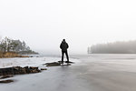 Man on rocks in frozen lake in Lotorp, Sweden