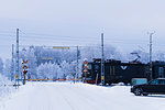 Car waiting on snowy road at railroad crossing