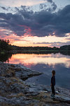 Woman standing by Lake Landsjon at sunset in Sweden