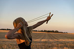 Teenage girl using sling shot in field