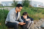 Father and son using a smart phone on grass