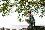 Boy crouching under tree