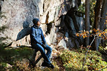 Man wearing beanie and jacket sitting by cliff