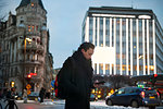 Young man holding cell phone walking down city street