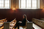 Priest with bible sitting on church pew