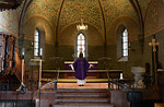 Priest in purple robes standing at chancel in church