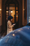 Young woman with afro hair using smartphone in front of building