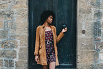 Young woman with afro hair waiting at door of stone building