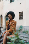 Young woman with afro hair waiting in front of building