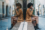 Young woman with afro hair having hot drink in front of cafe, Florence, Toscana, Italy