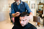 Hairdresser styling customer's hair in barber shop