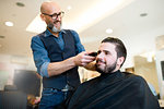 Hairdresser shaving customer's hair in barber shop