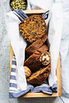 Still life of walnut and pumpkin seed cake sliced and  wrapped in tea towel in wooden box, overhead view