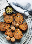 Still life of walnut and pumpkin seed cake sliced on cooling rack, overhead view