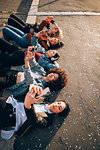 Friends together on kerb taking selfie and using smartphones, Milan, Italy