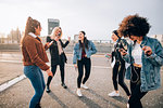 Friends dancing in street to smartphone music, Milan, Italy