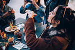 Friends taking photos of their food and drinks at outdoor cafe, Milan, Italy