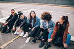 Friends sitting on kerb, Milan, Italy