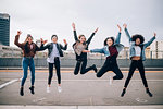 Friends jumping for joy in street, Milan, Italy