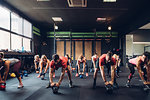 Women training in gym with male trainers, preparing to lift kettle bells