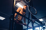 Young man training in gym, doing push ups on exercise bar