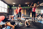 Group of women training in gym with male trainers, doing squats