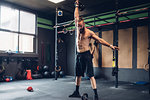 Young man training in gym, lifting kettle bell