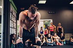 Bare chested young man in gym, bending forward exhausted