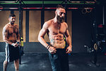 Young tattooed men training in gym, taking a break