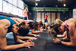 Women training in gym with male trainers, doing push ups