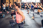 Group of women training in gym, with hands on hips and legs outstretched