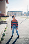 Young woman laughing on urban sidewalk, full length portrait