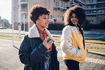 Two young women walking and talking on urban sidewalk