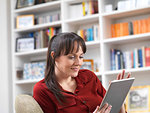 Woman relaxing at home on her digital tablet which she uses for social media, email and internet shopping