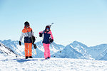 Teenage boy snowboarder with sister skier walking on snow covered mountain top,  Alpe-d'Huez, Rhone-Alpes, France