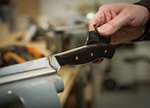 Knife factory worker applying wood stain to knife handle, close up of hands