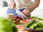 Man slicing red cabbage at kitchen counter, mid section