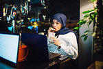 Young woman in hijab drinking smoothie in cafe