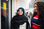 Young woman in hijab and friend on subway train