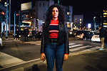 Mid adult woman with long curly hair on city street at night, portrait
