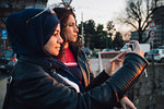 Young woman in hijab and best friend photographing from canal bridge in city