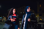 Young woman in hijab and best friend on city sidewalk at night