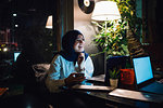 Young woman in hijab at a cafe table laughing
