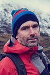 Male hiker in knit hat by snow capped mountains, close up portrait, Llanberis, Gwynedd, Wales