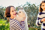 Girl and her friend holding a cute golden retriever puppy in orchard, Scandicci, Tuscany, Italy