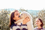 Girl with her friend holding up a cute golden retriever puppy in orchard, Scandicci, Tuscany, Italy